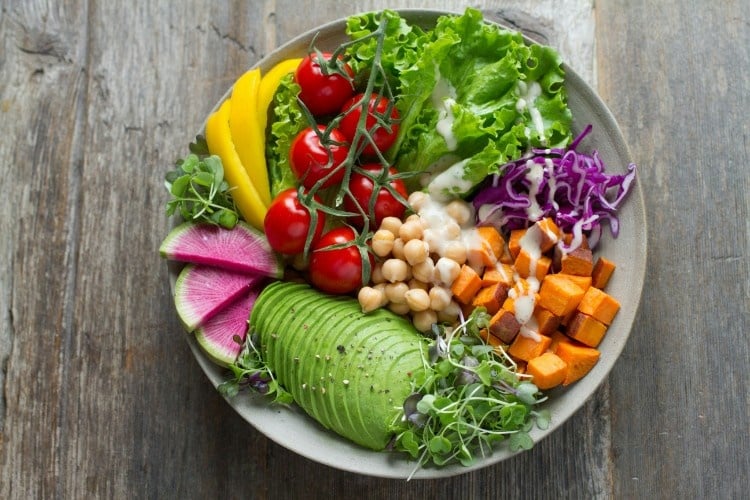 a healthy salad bowl full of colorful veggies including tomatoes, beans, radish, and greens